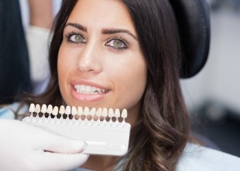 Dentist holding row of veneers in front of smiling patient