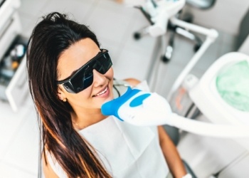 Woman receiving professional teeth whitening in dental chair