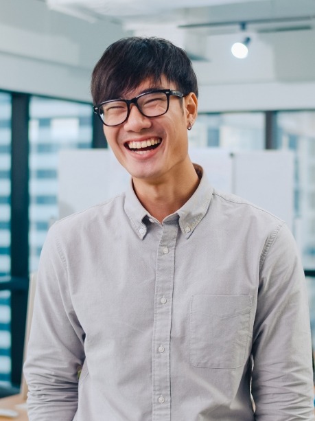 Young man with glasses smiling after dental checkup in Gorham