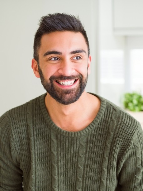 Young man in green sweater smiling with dental crowns in Gorham
