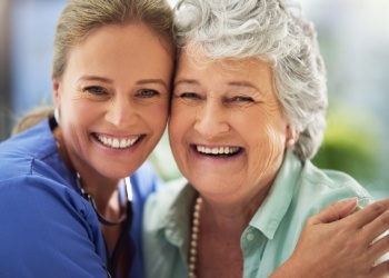Two women smiling and hugging side by side