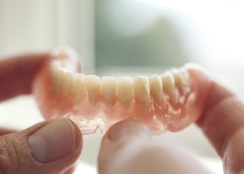 Hand holding a full denture