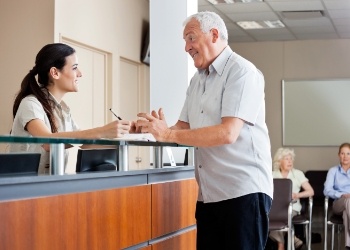 Senior man talking to dental office receptionist