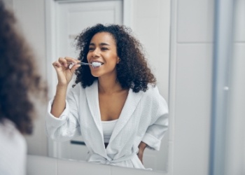 Woman smiling while brushing her teeth