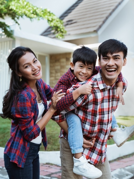 Family of three smiling in their front yard