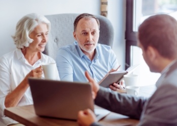 Man showing laptop to couple sitting across desk