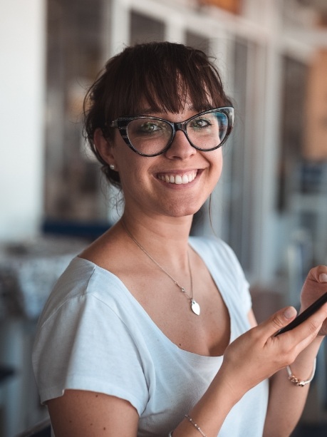 Young woman with glasses smiling after preventive dentistry in Gorham