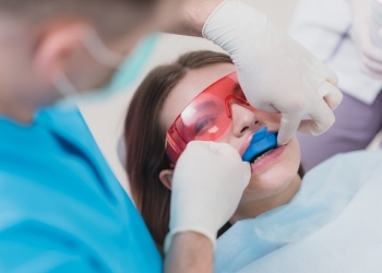 Young woman in dental chair having fluoride applied to her teeth