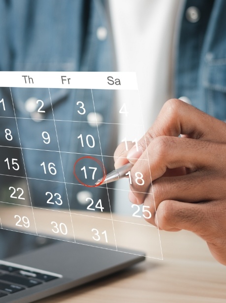 Person circling date of dental appointment on calendar