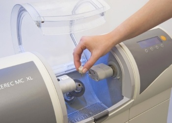 Dentist placing small ceramic block into milling machine