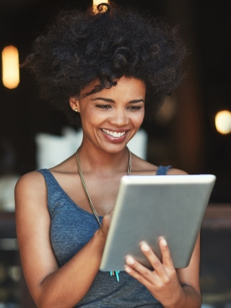 Woman using tablet to read dentist reviews in Gorham