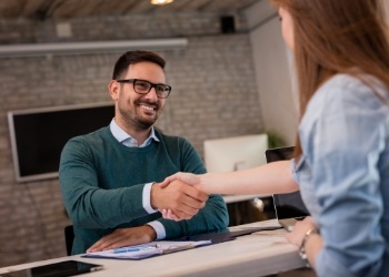 Man shaking hands with dental team member at front desk