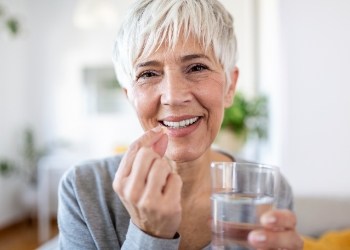 Woman holding a pill and a glass of water