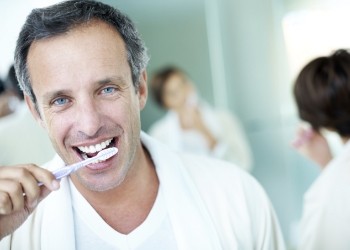 Man smiling while brushing his teeth