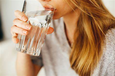 person drinking glass of water that contains fluoride