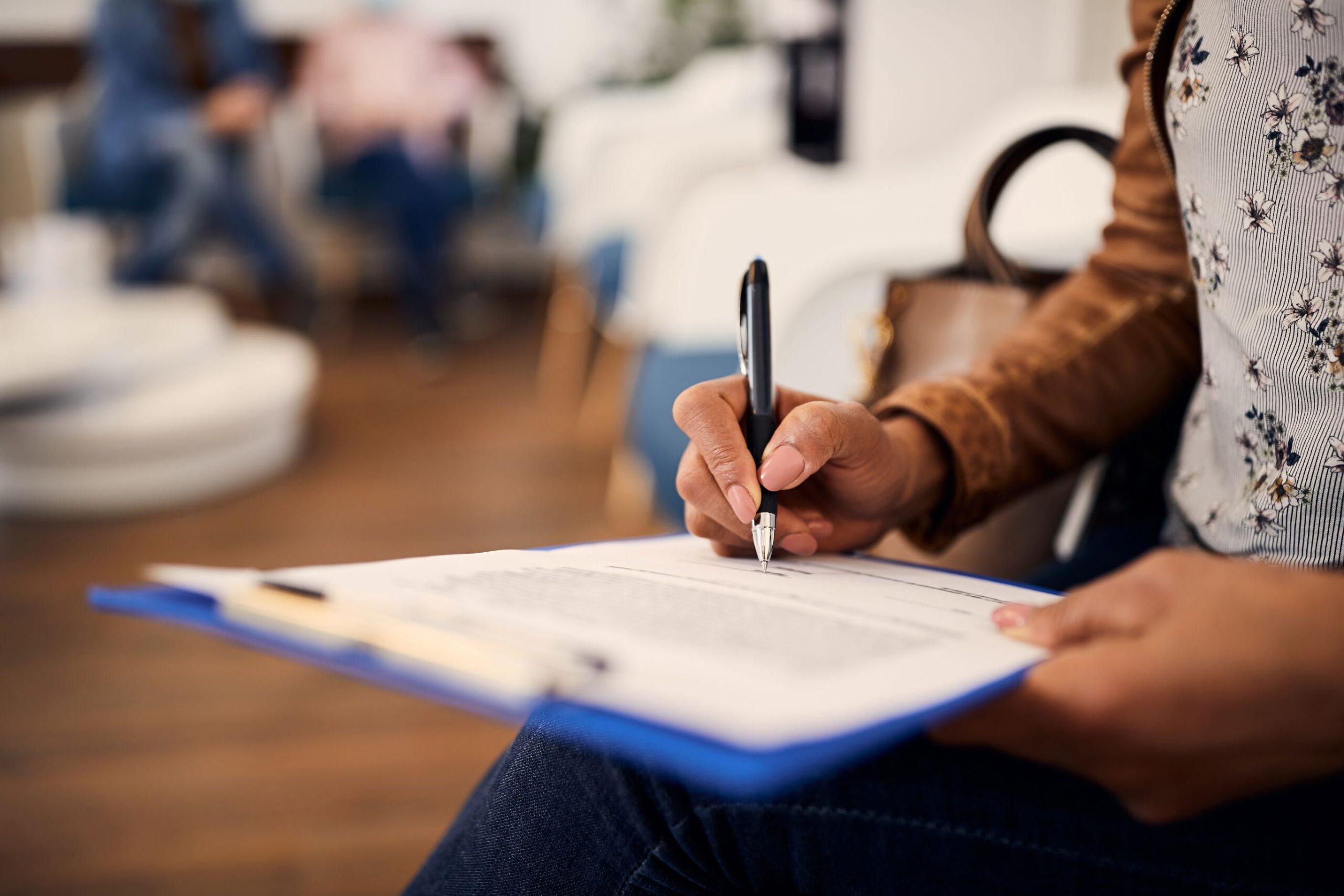 Woman's hands filling out insurance form on clipboard